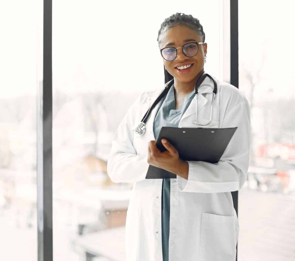 Professional female doctor smiling confidently holding a clipboard indoors.